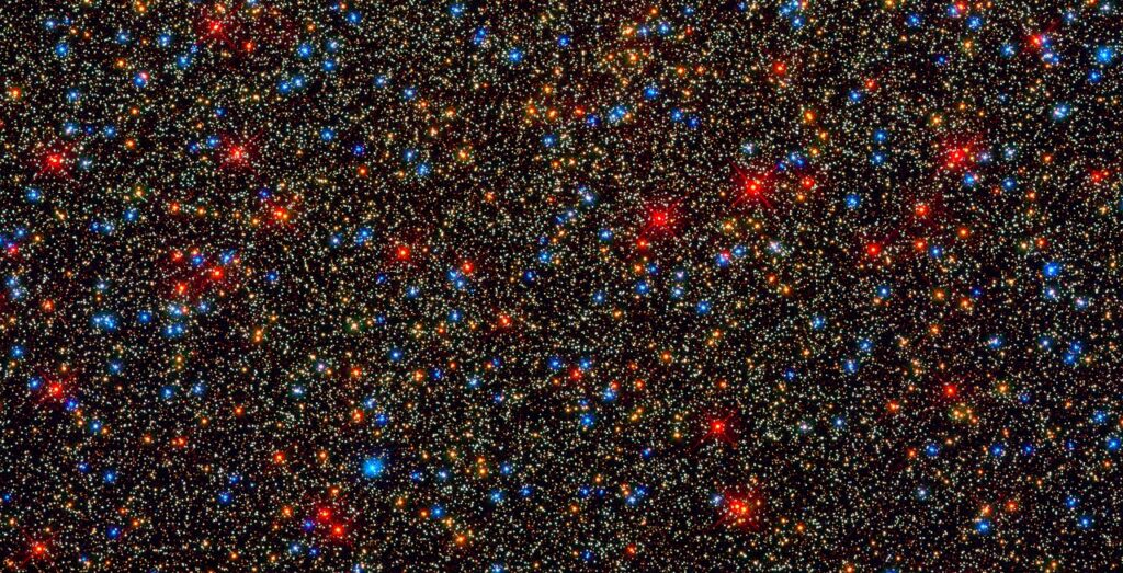 100,000個の星が写り込んだ壮観な画像で、色とりどりの星が一枚に収まっています。黄白色（太陽に似た主系列星）・橙色（晩年の星）・青白色（燃料を燃やし尽くしかけた星）・白色矮星が同時に写っており、「星には様々な種類がある」という記事の内容とまさに直結します。記事の「夜空の星のほとんどが主系列星」という話の視覚的な証拠にもなります。